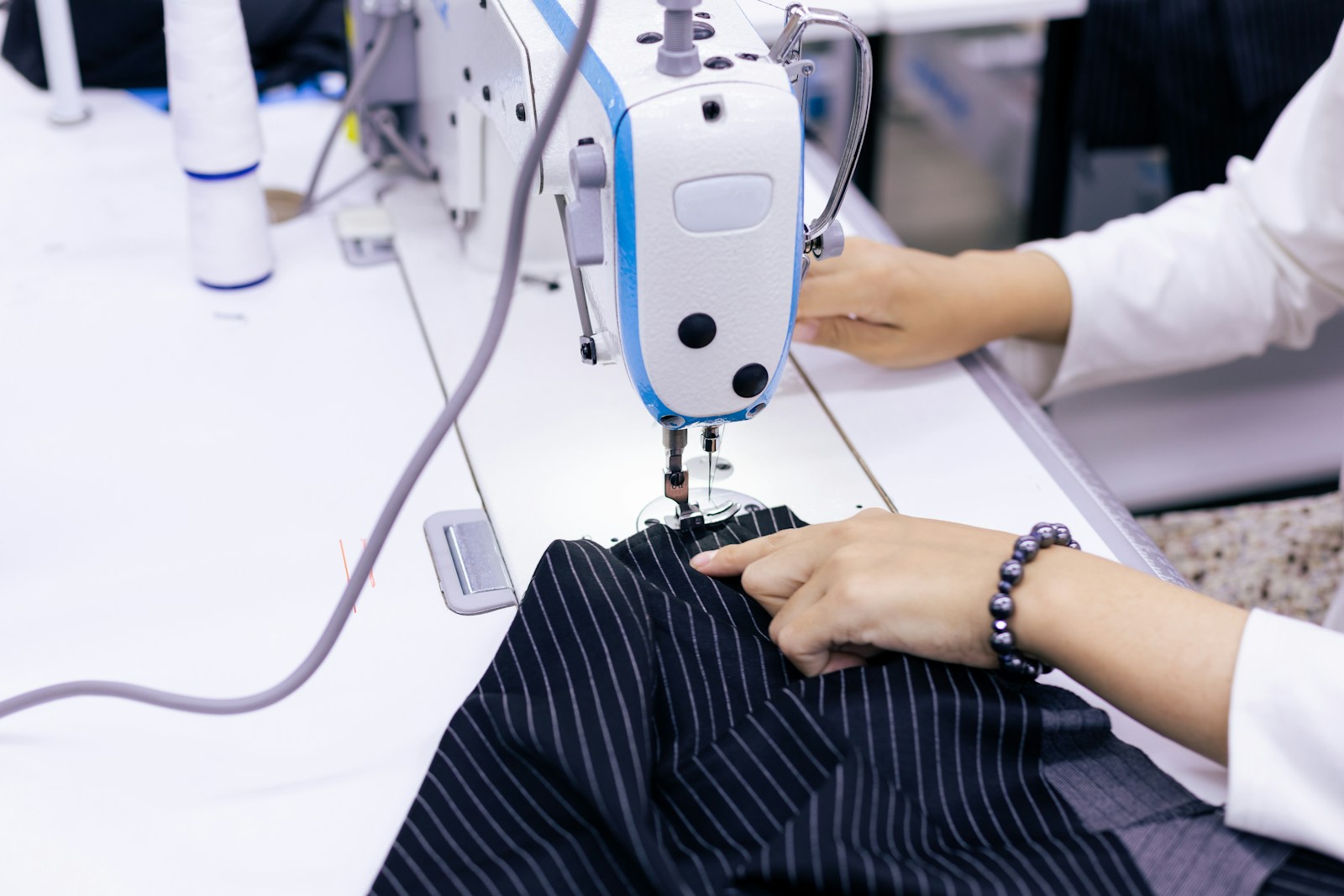 Manos confeccionando uniforme en máquina industrial